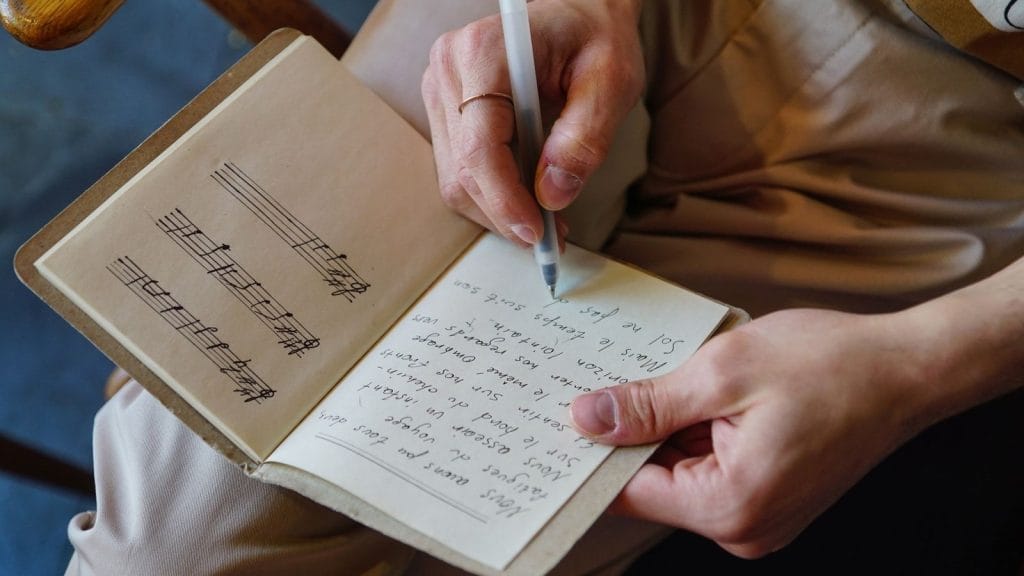 Handwritten wedding song lyrics and vows on a rustic table with wedding rings
